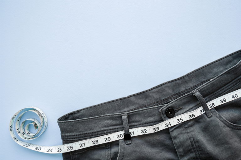 A pair of jeans with a BMI measuring tape on them.